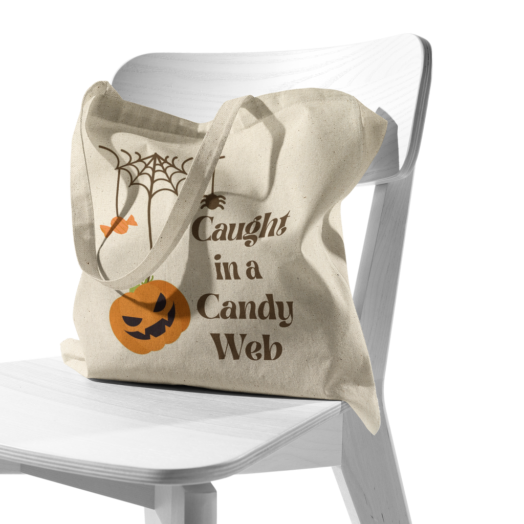 Caught_in_a_Candy_Web_Halloween_Tote_Bag_CottonTote_S_Chair_AS_Mockup.png